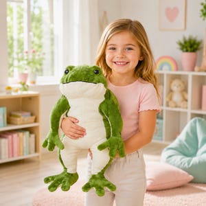 Könnte beinhalten: Ein Frosch-Stofftier mit einem leuchtend grünen Rücken und einem cremefarbenen Bauch. Das Kuscheltier hat große, dunkle, runde Augen, ein breites Maul und vier Schwimmfüße. Das Spielzeug ist aus einem strukturierten Stoff gefertigt und realistisch.