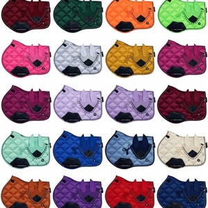 May include: A collection of twenty-four quilted horse saddle pads in various colors, each paired with a matching ear bonnet. The pads feature a diamond-stitched pattern, a reinforced girth area, and decorative braided trim along the edges.
