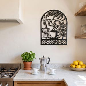 May include: A black metal wall art piece featuring an arched design with a moka pot, a steaming cup of coffee, coffee leaves, and a bottom border of coffee beans. The intricate cutout silhouette depicts a classic coffee brewing scene.