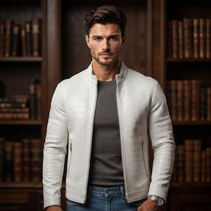 May include: A white jacket with a textured crocodile-skin pattern, featuring a stand-up collar and a central silver zipper. The jacket is worn over a dark gray t-shirt and blue denim jeans, with a silver wristwatch visible on the left wrist.