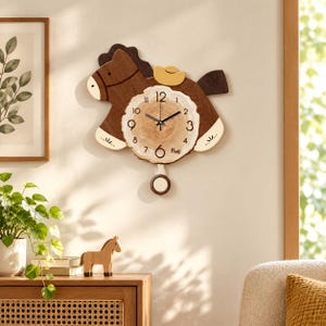 May include: A wall clock shaped like a brown horse with a light-colored wood slice face featuring black numbers, including the word Five, black hands, and a round pendulum. The horse has a dark brown mane, tail, and a small yellow saddle detail.