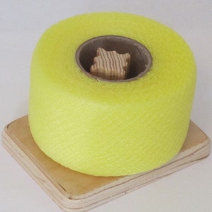 May include: A roll of bright yellow netting on a wooden base. The netting is wound around a cardboard tube.
