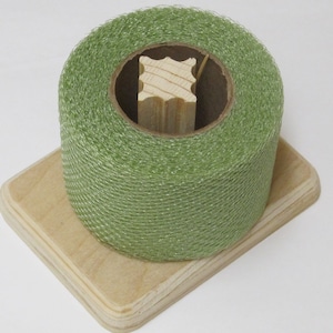 May include: A roll of green netting on a wooden spool, sitting on a wooden base.