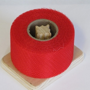 May include: A roll of bright red netting on a wooden spool. The netting is a fine mesh and is ideal for crafts or decoration.