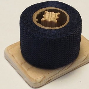 May include: A roll of dark blue fabric tape on a wooden base. The tape is wound around a cardboard core.
