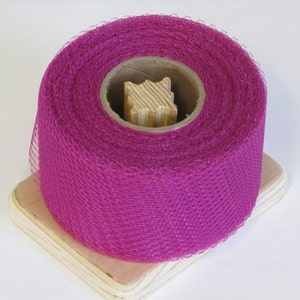 May include: A roll of bright pink tulle fabric on a wooden spool. The tulle is soft and delicate, perfect for crafting and decorating.