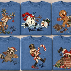 May include: A collection of six blue sweatshirts, each featuring a unique holiday-themed graphic and the text "Well, shit...". Designs include a tangled reindeer, a decapitated snowman, a burnt gingerbread cookie, a clumsy raccoon, a broken candy cane nutcracker, and Santa stuck in a chimney.