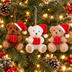Può includere: Tre ornamenti a forma di orsetto di peluche appesi a dei fili. Un orsetto è marrone scuro, uno è bianco e uno è marrone chiaro. Ogni orsetto indossa un cappello da Babbo Natale rosso con un pon-pon bianco e tiene un piccolo regalo rosso.