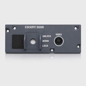 May include: A rectangular gray cockpit door control panel featuring white text labels. It includes a black square patch, a central circular opening with a protective guard, a three-position switch labeled UNLOCK, NORM, and LOCK, and a circular VIDEO port.