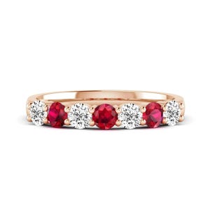 May include: A rose gold band ring featuring an alternating row of seven round-cut gemstones. The design includes four clear, sparkling white diamonds and three vibrant, deep red rubies set in a shared prong setting across the top.