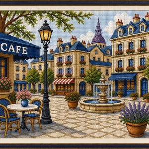 Peut inclure: Une broderie au point de croix représentant une place de ville européenne avec un café doté d'un auvent bleu marqué CAFE, un grand lampadaire noir, une fontaine en pierre et des immeubles à étages avec des toits bleus et des jardinières.
