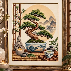 May include: A framed cross-stitch embroidery depicting a bonsai tree in a blue and white patterned pot, a seated Buddha statue, a lit candle, stacked dark stones, and a tea cup, set against a background of mountains and a large sun.