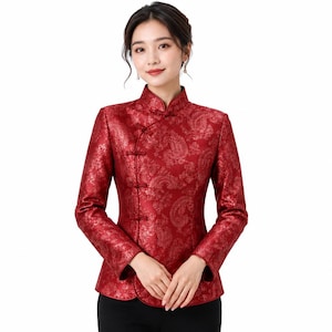 May include: A long-sleeved, deep red jacket featuring a mandarin collar and a side-fastening front with traditional fabric-covered knot buttons. The garment is crafted from a shimmering, textured fabric with an intricate, tonal paisley pattern.