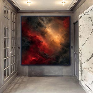 May include: A square wall art piece featuring an abstract depiction of swirling clouds in deep shades of crimson red, charcoal black, and glowing amber gold, framed in a thin black border and mounted on a gray wall in a hallway.