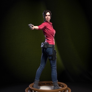 May include: A figurine of a character with dark hair in a ponytail, wearing a red long-sleeved jacket, blue jeans, and gray boots. The character holds a small silver handgun in one hand and has a black holster and belt pouch attached to their waist.