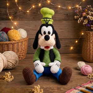 May include: A crocheted Goofy doll featuring a tall green hat, black ears, a beige muzzle with two white teeth, a green sweater, blue pants, and white gloves. The doll has black button eyes and a black nose, crafted with yarn in a seated position.
