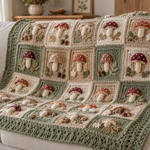 Könnte beinhalten: Eine Häkeldecke aus quadratischen Feldern mit dreidimensionalen Pilzmotiven in Creme-, Beige- und Salbeigrüntönen. Das Design zeigt verschiedene Pilzköpfe in Rot, Braun und Weiß und ist mit einer dekorativen grünen Bordüre versehen.