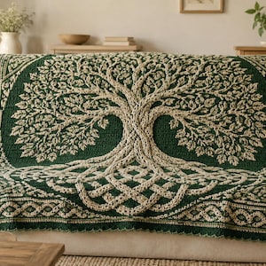 May include: A rectangular crochet blanket featuring a dark green background with a large, central tree design in cream yarn. The tree has intricate, textured branches and roots, surrounded by a detailed cream-coloured border with a woven knot pattern.