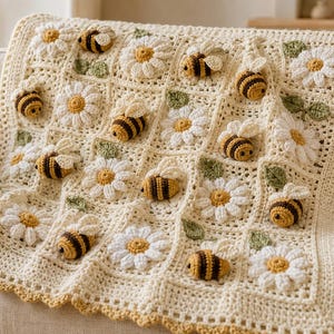 May include: A cream-colored crochet blanket featuring a repeating grid pattern of three-dimensional white daisy flowers with yellow centers, small green leaves, and stuffed bumblebees with black and yellow stripes and white wings.