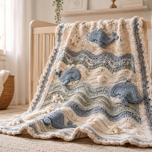 Peut inclure: Une couverture en crochet de couleur crème présentant des rayures horizontales ondulées dans des tons de bleu et de vert sauge. La couverture est ornée de baleines bleues en crochet en relief, de petites étoiles de mer blanches et de coquillages.