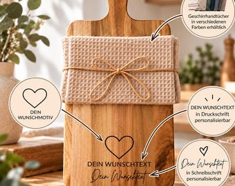 Könnte beinhalten: Ein rechteckiges Holzschneidebrett mit Griff und Loch, darauf ein beiges Waffel-Geschirrtuch, das mit einer Kordel umwickelt ist. Das Brett ist mit einem Herzsymbol sowie dem Text DEIN WUNSCHTEXT und Dein Wunschtext graviert.