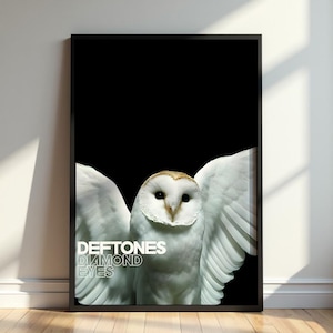 Peut inclure: Une impression murale rectangulaire encadrée représentant une chouette effraie blanche aux ailes déployées sur un fond noir uni. Le texte "DEFTONES" et "DIAMOND EYES" est imprimé en lettres capitales blanches sur le côté inférieur gauche.