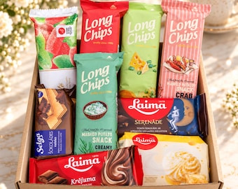 Può includere: Una scatola di cartone riempita con varie confezioni di snack, tra cui patatine Long Chips in buste rosse, verdi e rosa, barrette di cioccolato Laima, wafer al cioccolato Selga e un dolcetto al marshmallow Laima giallo, disposti ordinatamente.