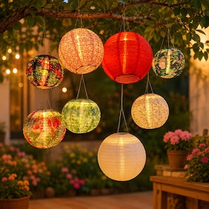 Peut inclure: Un ensemble de huit lanternes sphériques suspendues aux branches d'un arbre. Les lanternes présentent divers motifs, notamment des surfaces rouge uni, blanc uni et imprimées avec des motifs floraux, botaniques et géométriques, toutes éclairées de l'intérieur.