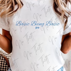 May include: A white short-sleeved t-shirt featuring the blue text Basic Being Basic printed on the front. The shirt has a crew neckline and a standard fit. The fabric is plain white, and the design is centered on the chest area of the garment.