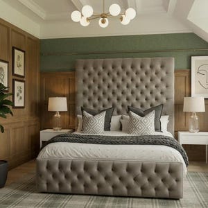 May include: A tall, tufted, light grey upholstered bed frame with a high headboard and matching footboard. The bed is dressed in white bedding, a dark grey knit throw blanket, and two square throw pillows featuring a white and grey geometric pattern.