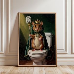 May include: A framed wall art print depicting a brown hamster wearing a gold crown and a dark green hooded cape. The hamster stands on a white toilet lid, holding a long silver and gold toilet brush like a scepter in a dark bathroom setting.