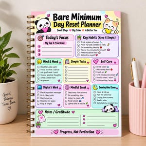 Può includere: Un'agenda a spirale Bare Minimum Day Reset Planner con una combinazione di colori pastello. La copertina presenta illustrazioni di un panda e di un gatto, con sezioni per priorità giornaliere, abitudini, umore, compiti e cura di sé.