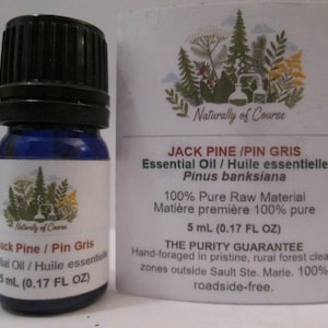 May include: A small blue glass bottle of Jack Pine essential oil with a black cap and a white label featuring a forest illustration and the text Naturally of Course, Jack Pine / Pin Gris, 5 mL (0.17 FL OZ), and 100% Pure Raw Material.