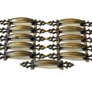 May include: A collection of antique bronze-colored drawer pulls. Each pull features a textured, curved handle with decorative diamond-shaped accents on each end. The hardware is arranged on a white background.