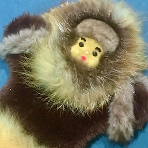 May include: Vintage fur pin featuring a small doll-like figure with a painted face, wearing a fur-trimmed hood. The fur is a mix of brown, tan, and gray. The text "DSTROVEVINTAGE" is at the top.