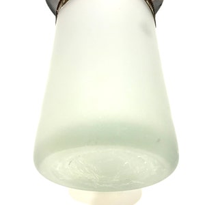 May include: A frosted glass lampshade with a decorative purple and gold top. The lampshade has a conical shape and a textured surface. The top features a decorative design with purple and gold accents.