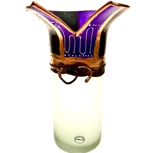 May include: A frosted glass vase with a flared, decorative top. The top features a purple and gold design with white accents. The vase has a cylindrical shape and a decorative wire detail around the middle.