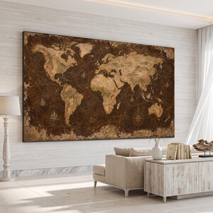 Op de afbeelding: Een groot rechthoekig wandkunstwerk met een wereldkaart in vintage-stijl, voorzien van een donkerbruine, verweerde achtergrond en beige continenten. De kaart toont gedetailleerde navigatielijnen, maritieme illustraties en een kompasroos.