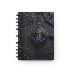 Puede incluir: Un cuaderno de espiral con una cubierta oscura y texturizada que presenta un intrincado marco metálico en relieve alrededor de un ojo morado realista en el centro. El diseño incluye patrones de filigrana oscuros y adornos morados, creando una apariencia detallada y superpuesta en la portada.
