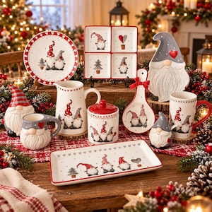 May include: A collection of white ceramic kitchenware featuring gnome illustrations, red and gray accents, and heart motifs. The set includes a round plate, a four-section tray, a pitcher, a lidded canister, a spoon rest, mugs, and a rectangular tray.