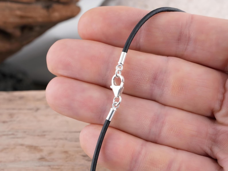 Sterling silver clasp on black leather necklace held in hand.