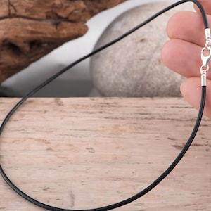 Black leather necklace held in hand for scale.