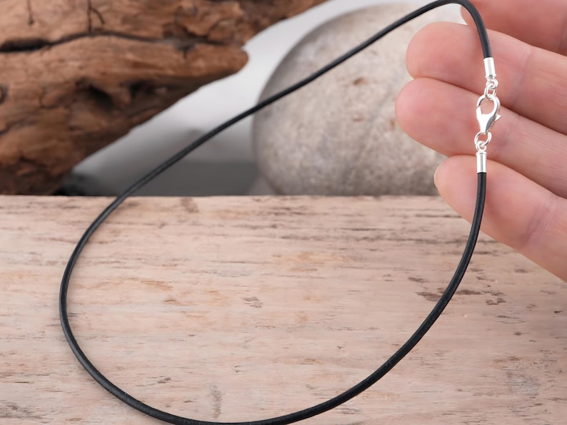 Black leather necklace held in hand for scale.