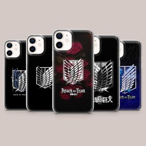 Può includere: Cinque cover trasparenti per telefono con l'emblema Ali della Libertà di Attack on Titan. I design includono un logo bluastro, un logo bianco su nero, una cover centrale con rose rosse e testo, e una cover con stampa galassia blu.