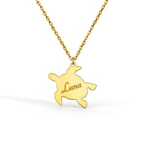 Peut inclure: Un collier doré avec un pendentif en forme de tortue marine. Le centre du pendentif tortue est gravé du prénom Luna dans une police d'écriture cursive. Le pendentif est suspendu à une fine chaîne dorée composée de petits maillons.