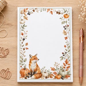 May include: A rectangular notepad featuring a white centre and a decorative border of watercolour illustrations including orange pumpkins, brown acorns, dark berries, and autumn leaves, with a fox sitting at the bottom centre of the page.