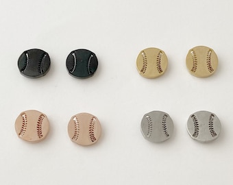 May include: Six pairs of baseball-shaped earrings in different metal finishes: black, gold, rose gold, and silver.
