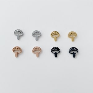 Peut inclure: Huit breloques en forme de champignon en métal de quatre couleurs différentes : argent, or, or rose et noir. Les breloques sont toutes de la même taille et de la même forme, avec un design de champignon détaillé.