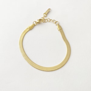 May include: A gold-toned snake chain bracelet with a lobster clasp closure.