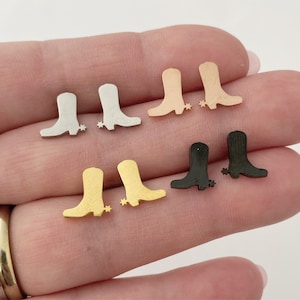 May include: Six pairs of cowboy boot earrings in different metal finishes: silver, gold, rose gold, and black. The earrings are small and delicate, perfect for adding a touch of western style to any outfit.